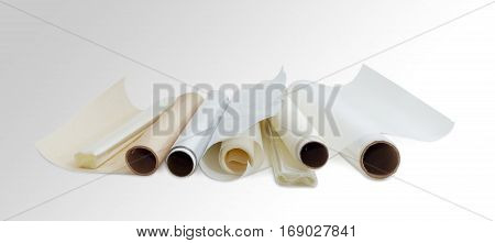 Several rolls of the plastic oven bags plastic food wrap aluminum foil and various parchment paper for household use on a light background.
