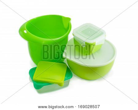 Several different green reusable plastic food storage and cooking containers some with covers for home use on a light background