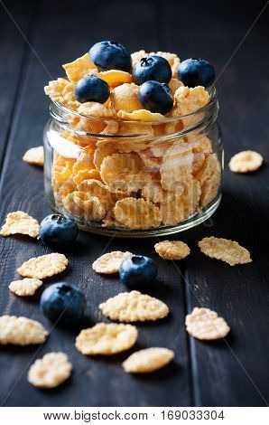 Close up of cornflackes with blackberries in jar on dark wooden background selective focus vertical. Healthy food concept.