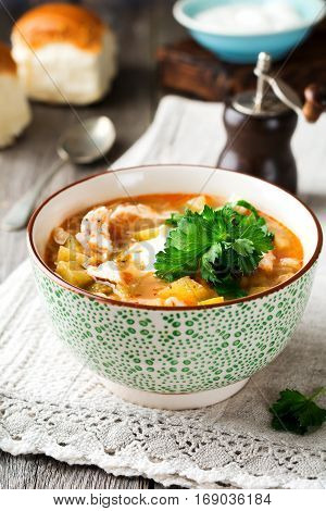 Traditional Russian soup-Rassolnik wit hpickled cucumber barley chicken tomatoes and parsley in ceramic bowl. Selective focus.