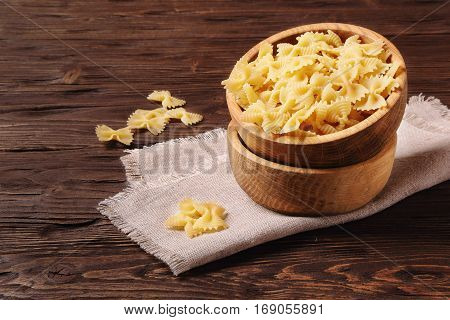 Pasta farfalle in a wooden bowl on the table
