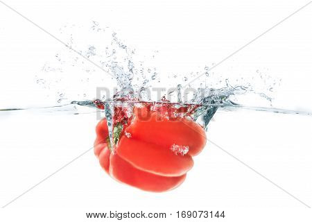 Red bellpepper dropped into the water with water splash on a white background