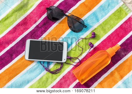 Travel essentials for beach summer vacation. Suntan accessories. What to bring on a holiday trip to the Caribbean: Music phone app and earphones, smartphone, sunglasses, sunscreen.