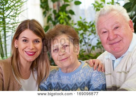 Picture of a senior couple with their cheerful caregiver at home