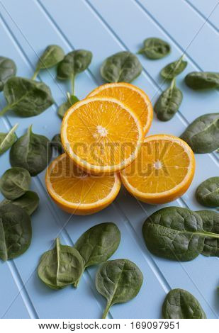 Slices of orange and green leaves on a blue background. Vegetarin. Raw food diet