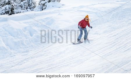 girl goes on a snowboard at the ski slopes in winter down from a hill on the move
