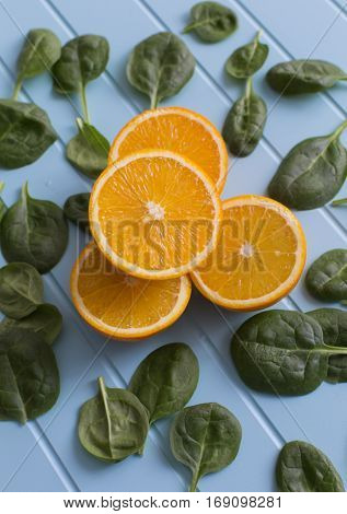 Slices of orange and green leaves on a blue background. Vegetarin. Raw food diet