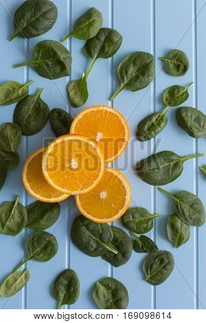 Slices of orange and green leaves on a blue background. Vegetarin. Raw food diet