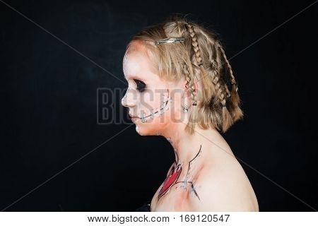 Teen Girl with Halloween Makeup. Profile on Blackboard Background
