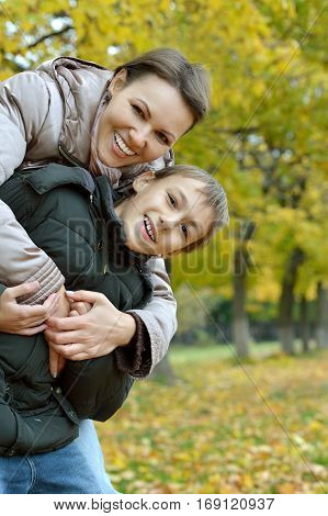 Beautiful mother with a boy on a walk during the fall of the leaves in the park