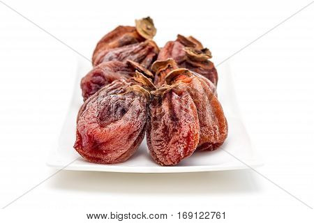 Several dried persimmon isolated on white plate