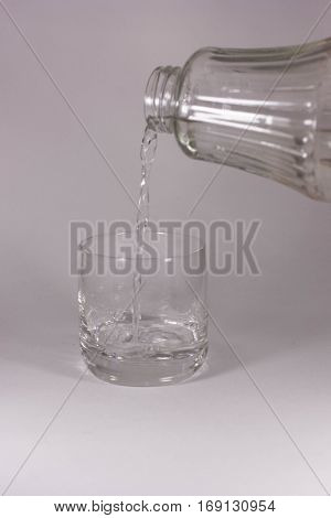 Water is poured into a glass on a white backgroundc
