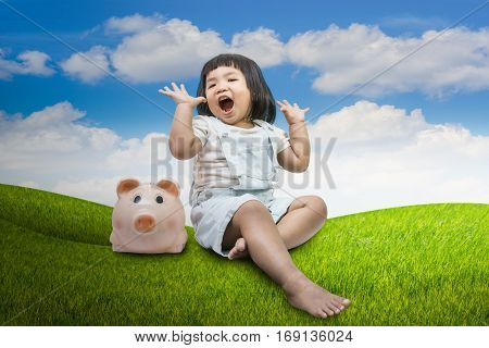 conceptual image happy child little girl sitting close a piggy bank on white background.