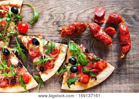 Hot pizza slice with Pepperoni melting cheese on a rustic wooden table close up.