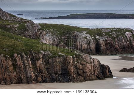 North Coast Scotland - June 6 2012: Cliffs descend on Durness Beach a sandy patch looking north on a rough coast among rock cliffs and sprinkled pieces of rock.