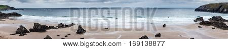 North Coast Scotland - June 6 2012: Panorama shot. Durness Beach is a sandy patch looking north on a rough coast among rock cliffs and sprinkled pieces of rock.