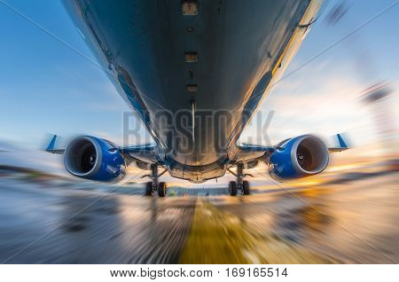 Airplane in motion during takeoff and landing, on a background of sunset and wet runway