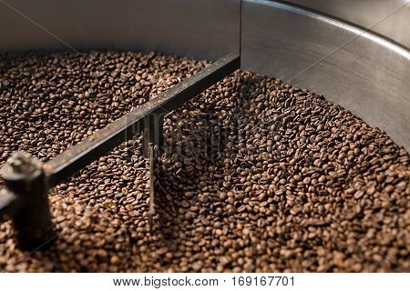 Freshly roasted coffee beans get sifted and stirred in  roasting machine