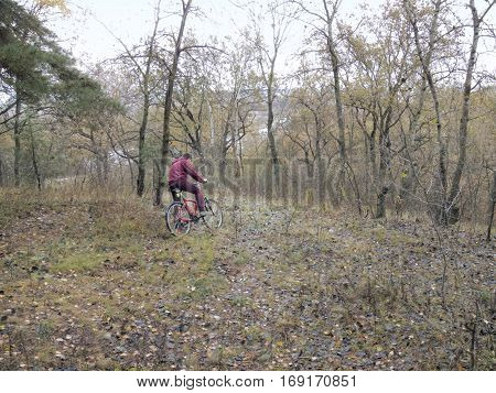 guy on the red bicycle stopped in the uncharted rugged terrain