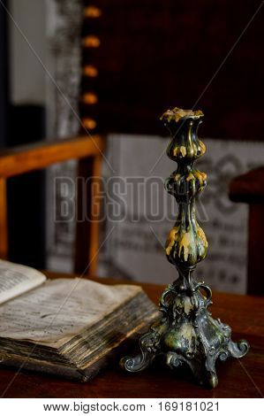 Still life on a table with an old book and a beautiful candlestick.