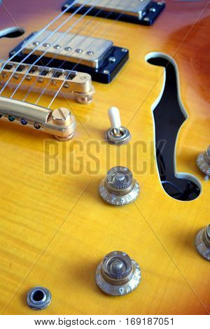 Part of vintage semi-hollow body electric guitars with pickups, electronics knobs and metal accessories closeup