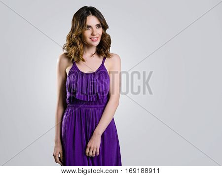 Beautiful brunette in violet dress on light background