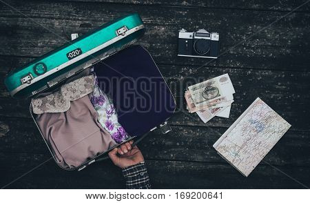 Vintage hipster suitcase packing before travel with old suitcase camera and accessories on a wooden table top view
