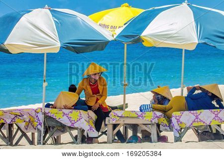 PHU QUOC, VIETNAM - APRIL 21, 2014: Beach masseuses resting  waiting of tourists in the shade of umbrellas at Long beach on Phu Quoc island, Vietnam. 