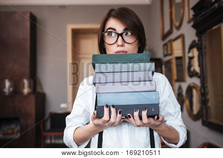 Authoress in glasses and white shirt holding books and looking away