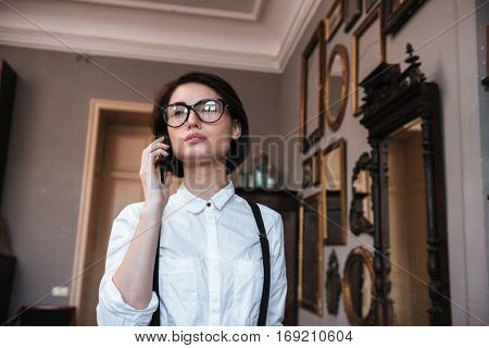 View from below of Authoress in glasses and white shirt talking on phone