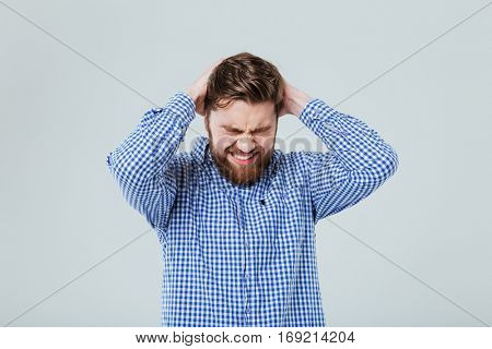 Stressed bearded young man with closed eyes having headahce