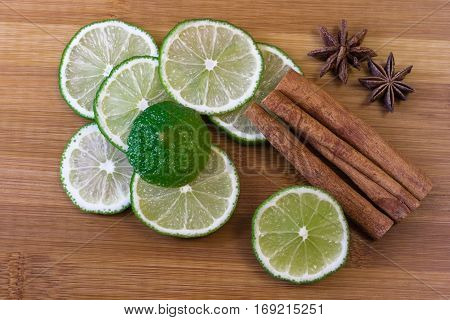 Green lime slices with cinnamon sticks on a bamboo board
