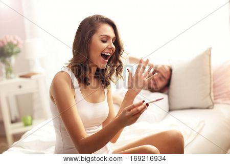 Picture showing woman with pregnancy test in bedroom