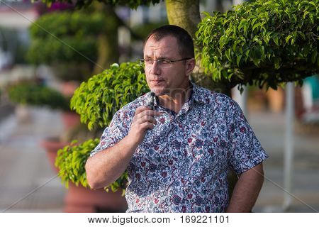 Adult senior man vaping electronic cigarette outdoor.