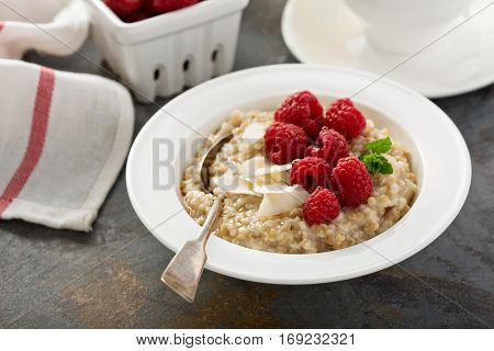 Steel cut oatmeal porridge with raspberry and coconut flakes for breakfast