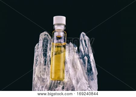 Detail of cannabis oil container and quartz crystal isolated on black - medical marijuana concept