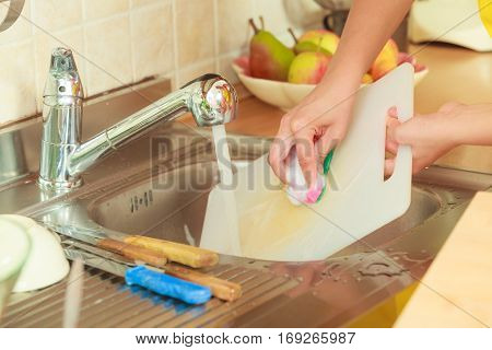 Household. Closeup woman doing the washing up in kitchen cleaning plastic cutting board