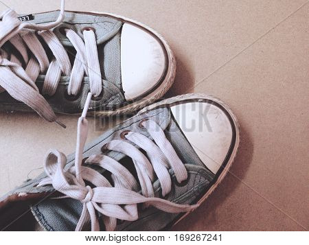 Dirty shoes top view of blue sneakers display on brown background. Vintage effect.