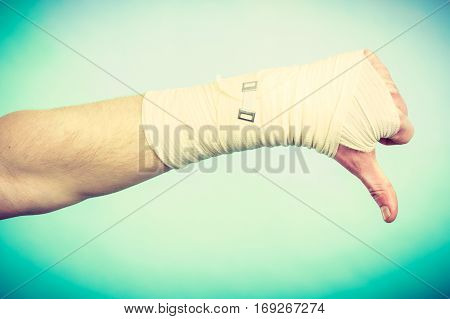 Bad news and information. Medicine aspects. Male hand with bandage showing thumb down sign symbol.