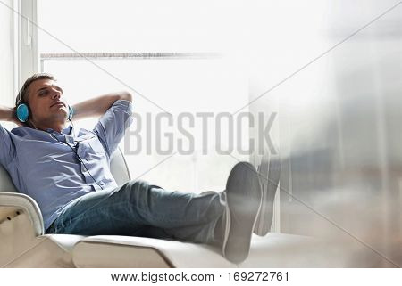 Full-length of relaxed Middle-aged man listening to music at home