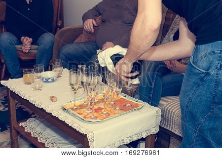 Pouring champagne at family celebration. Closeup of homely athmosphere.