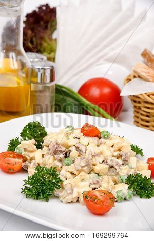 Salad of veal with mustard and mayonnaise on a white plate with fresh herbs