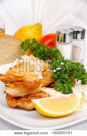 Perch in batter with herbs and spices on a white plate