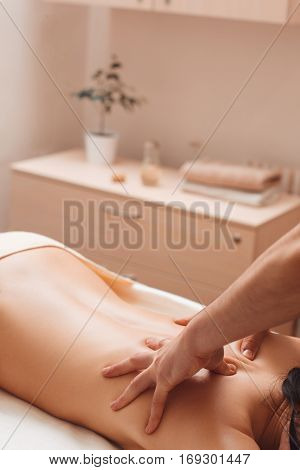 Masseur hands massaging female back free space. Nude woman relaxing at spa salon, having treating procedures. Beauty, health, body care, weight loss, rest, pleasure, craftmanship concept