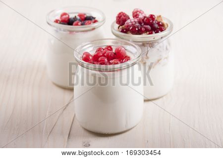 Homemade yogurt with frozen berries red currants black currants raspberries and cranberries in three banks