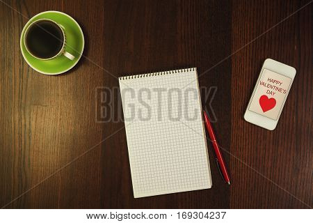 close-up, pen, notepad near phone and cup of coffee at wooden desk