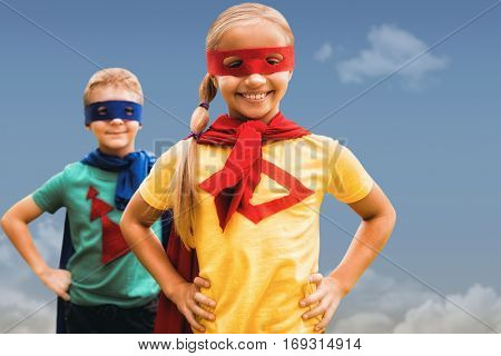 Siblings with hands on hip against blue sky