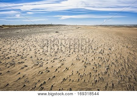 west coast on a beautiful summer day with blue sky, white clouds and many small stones in the sand