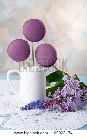 Purple French macaroons cookies and marshmallow on a stick in a vase like a bouquet lilac flowers