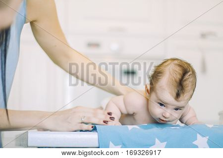 small child learns to help parents keep his head. baby lying on a blue diaper in a star. parental support.